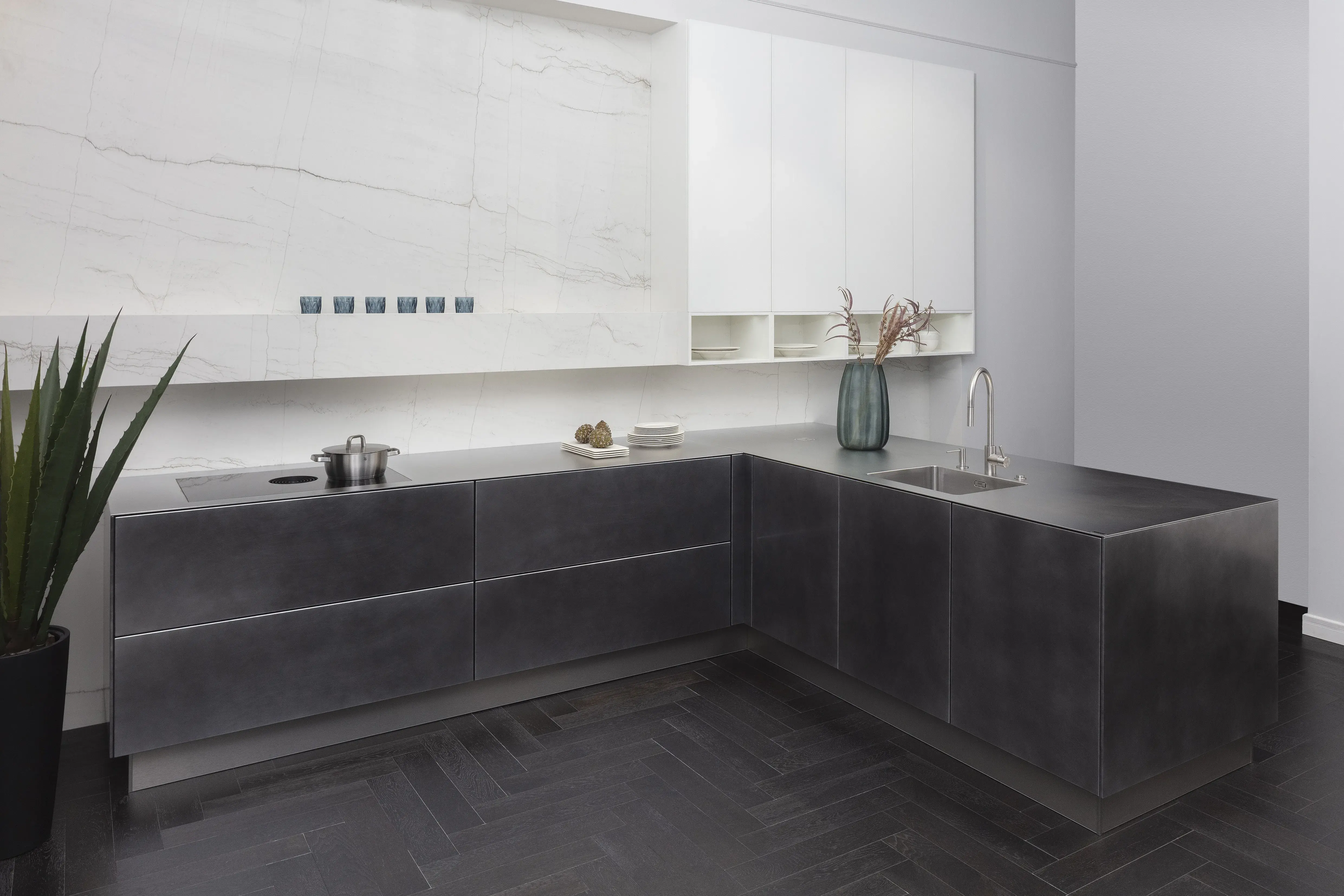 Front: Industriestahl Metalliclack geschliffen AV6000 NCS Mattlack APL: Franke Edelstahl 6 mm Geräte: Bora Spüle Armaturen: Franke  Features: Metallfront, Spülbecken in APL integriert (aus einem Guss), Oberschränke mit Lowboard-Charakter, integrierter Arbeitsplatz, dunkler Korpus mit Aluminium-Abschlussleiste, Wärmeschublade mit Gittereinsatz.